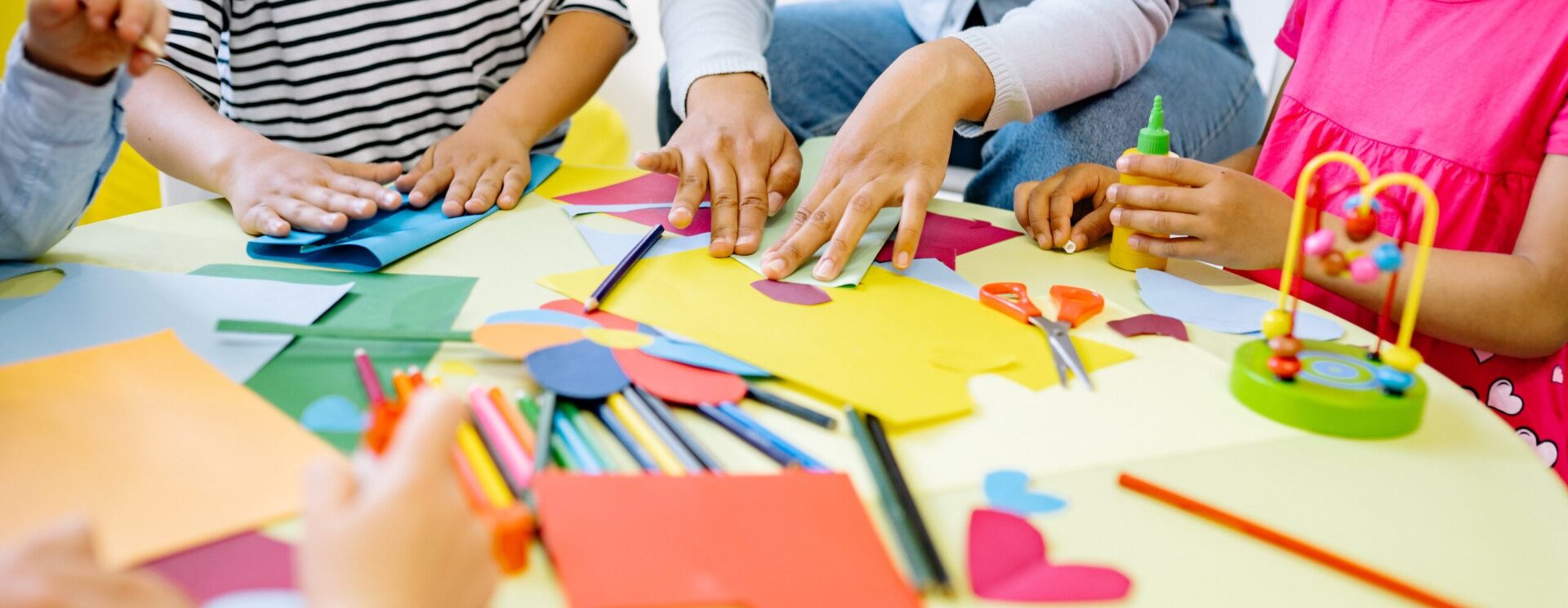 Mains d'enfants qui font de la peinture avec un adulte dans une classe